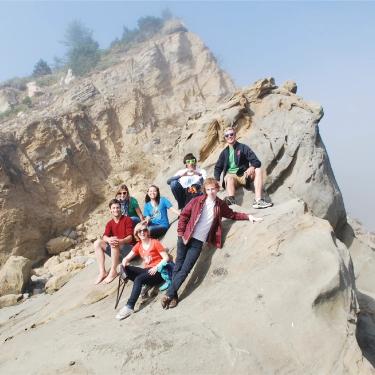 A group of students post on a the top of a sand dune.