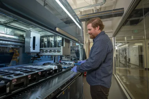 A person stands in front of a liquid handling platform in the G C 3 F core facility.