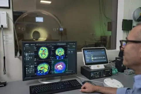 A person looks at M R I scans of a brain on a computer screen.