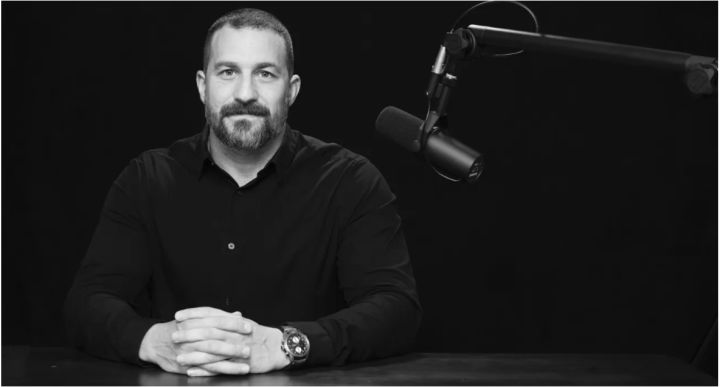 Portrait of Dr. Huberman in black and white siting in front of an audio microphone