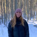 Woman in front of snowy trees. 